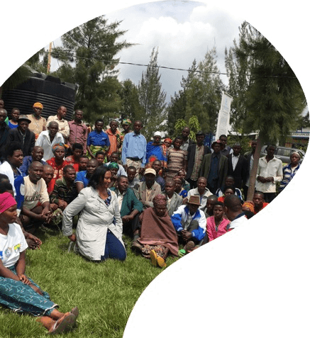 Farmers and cooperative members of the wider Kalisimbi Kiwieds family, gathered together on the grass.